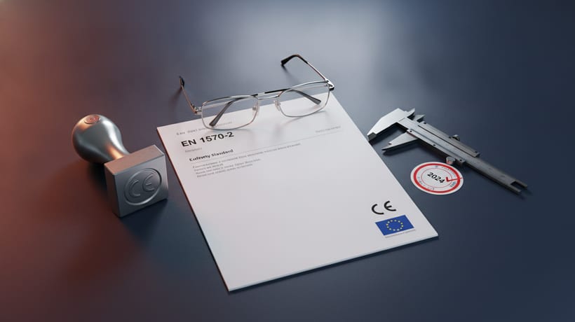 EN 1570-2 standard document with CE stamp, caliper and inspection badge on an engineering desk